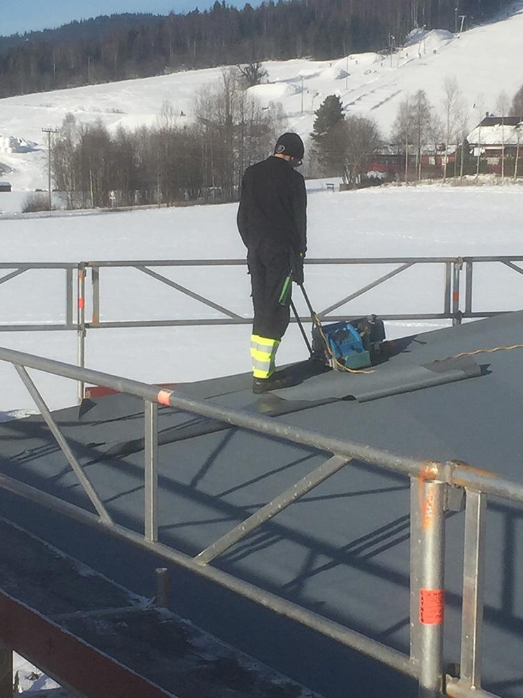 En taktekker på et flatt tak med snø rundt